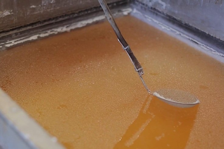 釜炊きでアメ色になった海水から塩の結晶をすくう