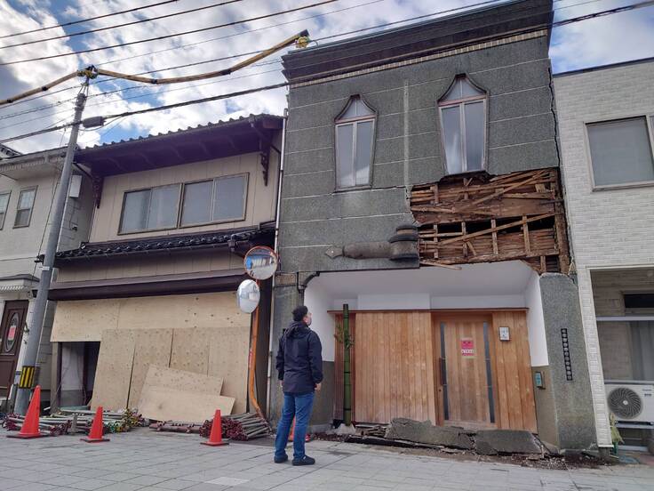 外壁が剥がれ落ち、内部にも歪みが出ている店舗を見つめる川嶋氏