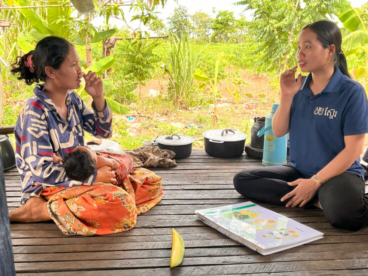 お母さんに話をする保健ボランティアさん（右）