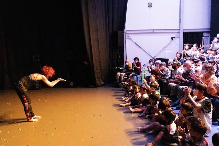 公開リハーサルの様子。客席に座る保育園児に、アーティストが話しかけている。