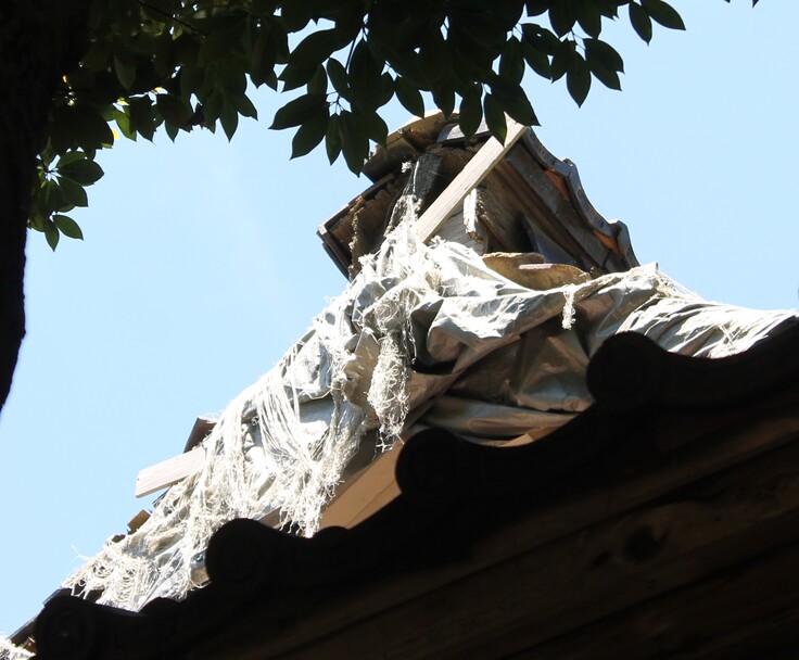 応急処置が施された屋根の頂部：痛みが激しく一部はビニールシートで応急的に覆われている状態です。このままでは雨漏りが進行し、建物全体の劣化につながりかねません。早急な修理が必要です。