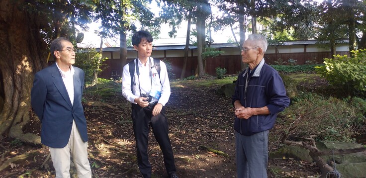 庭にて、読売新聞の取材に応じるご当主・保存会会長（中央は記者）。