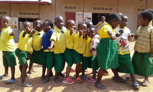 支援予定の校舎の前でポーズを決める園児たち