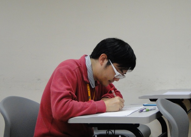 選手のスピーチを聞きメモを取る台湾人の主審