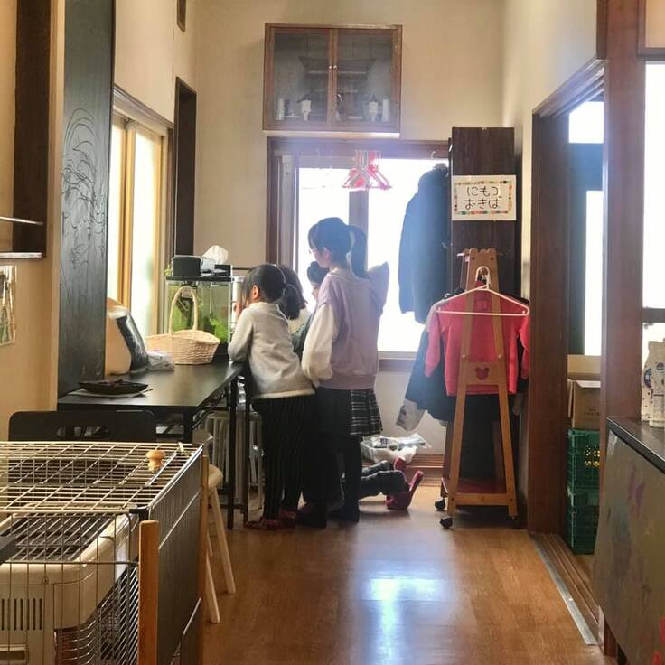 広くなった新子ども食堂で弱視のスタッフに卵を抱えたメダカを説明する子どもたち