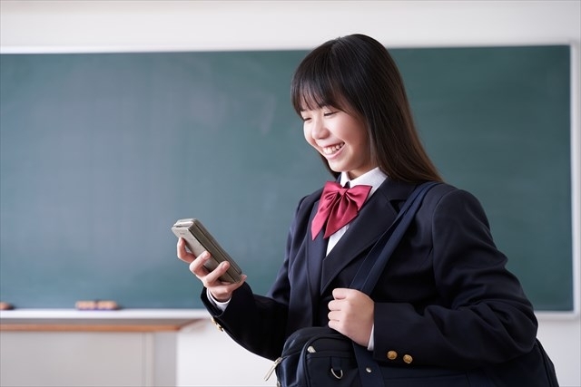 笑顔でスマホを見る女子高校生
