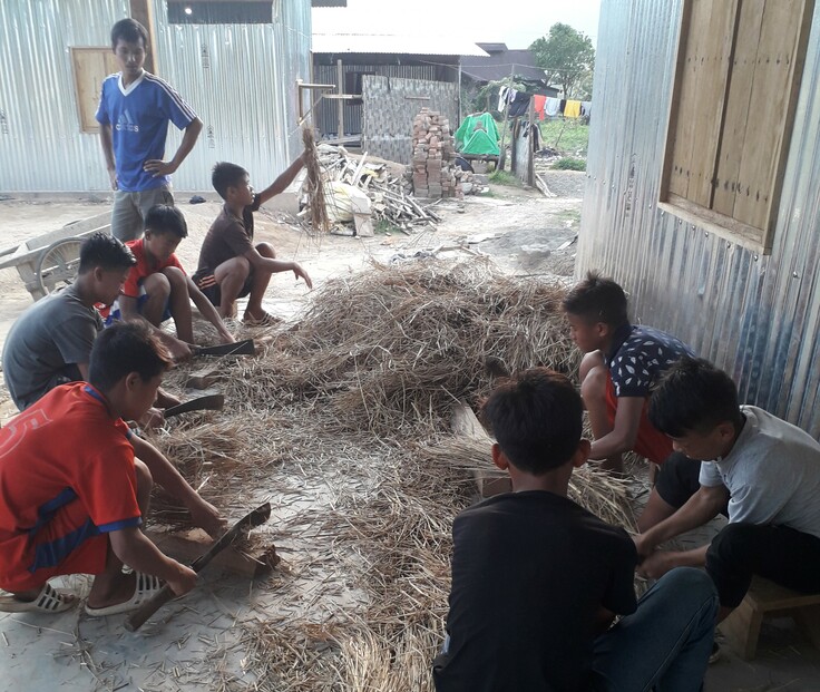 2019年、学校の生徒たちにきのこ栽培技術を伝達する代表者の夫。きのこの菌床を植える稲わらを細かく砕いているところ。