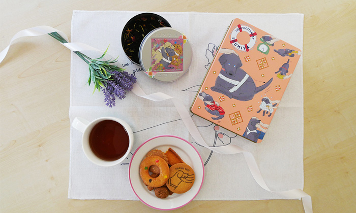 チャリティーグッズの写真。クッキー缶とお茶が並ぶ。