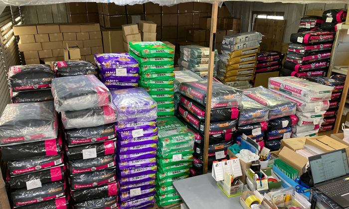 ドッグフードの倉庫画像。大きな袋のフードが積み上げられ、ぎっしりと並んでいる。