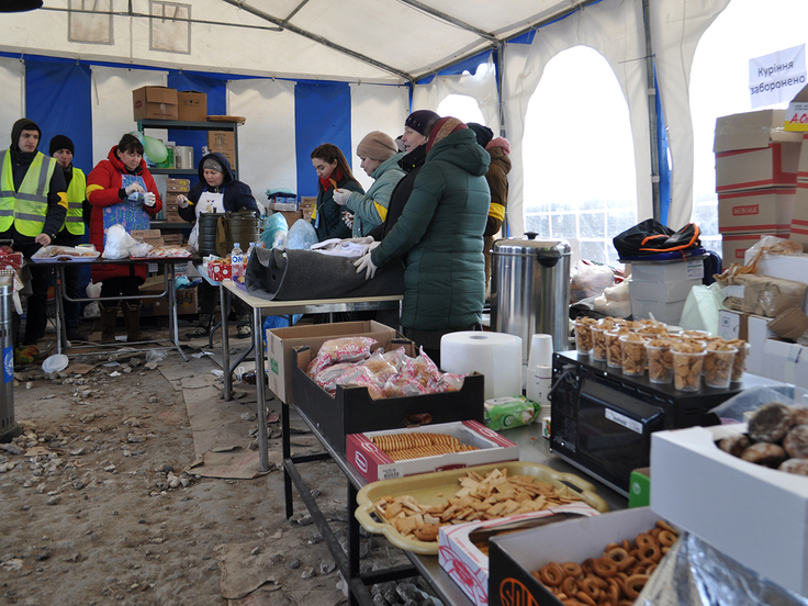 テントの中でたくさんの食料が並び、それを配るボランティアが立っている様子
