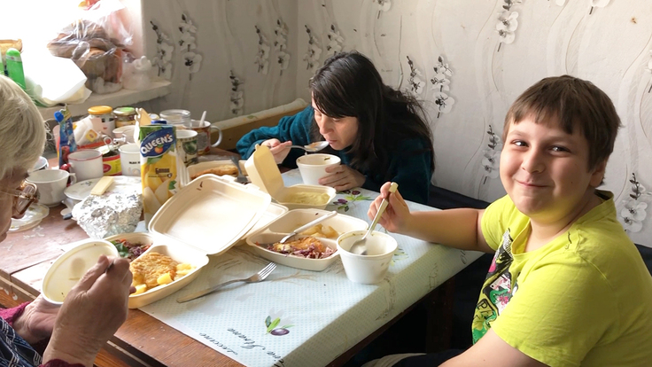 AARからの食事をとり笑顔のウクライナ避難民家族3人　右は笑顔の男の子
