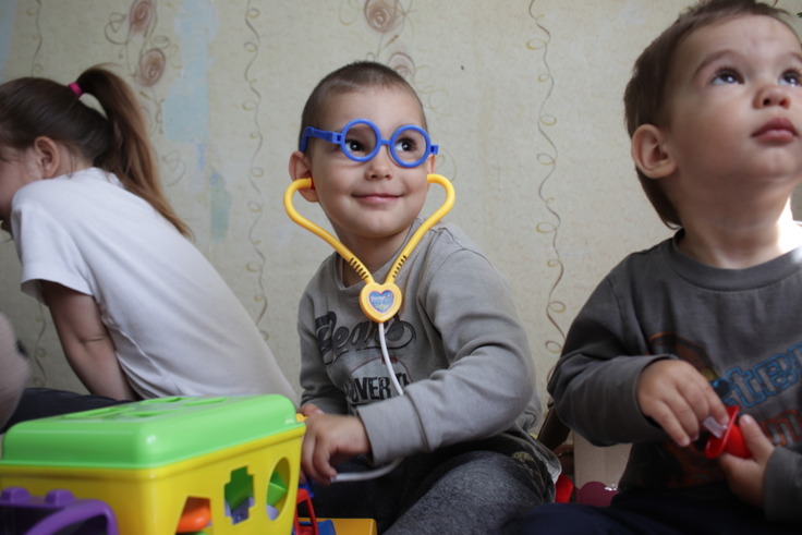 おもちゃのメガネと聴診器をつけて笑顔の子ども
