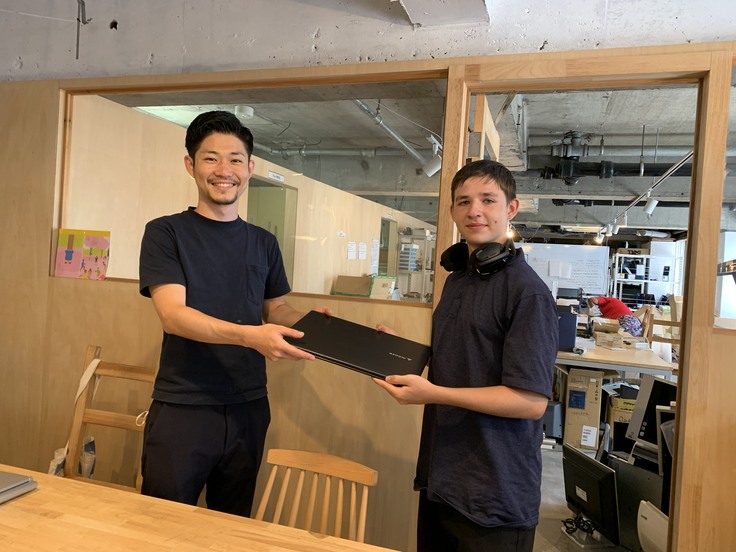 ピープルポートの青山明弘社長（左）から、パソコンを受け取るアルテムさん