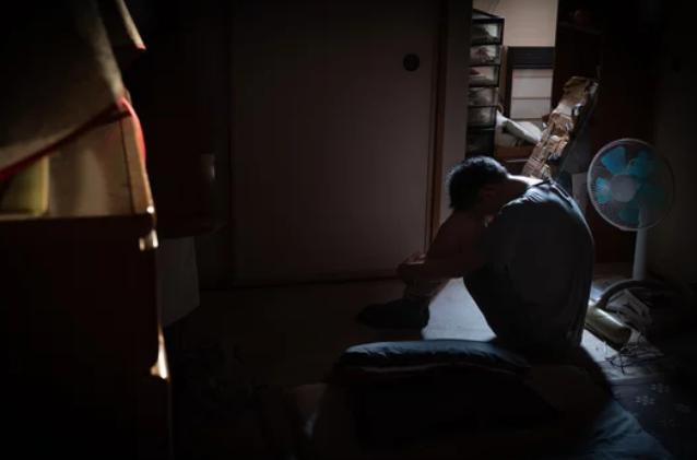 暗い部屋の中で座り込んでいる男性